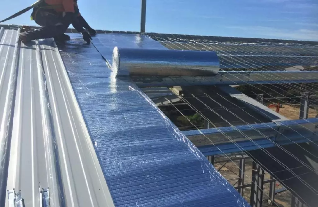 Worker Applying Insulation on a Metal Roof