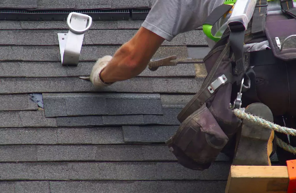 Roofing Technician Hammering Shingles on a House
